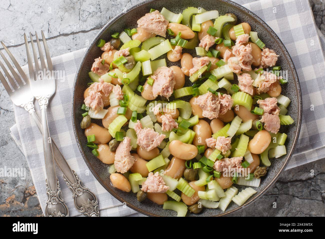 Canned tuna salad with butter beans, celery, green onions and capers close-up in a plate on the table. Horizontal top view from above Stock Photo