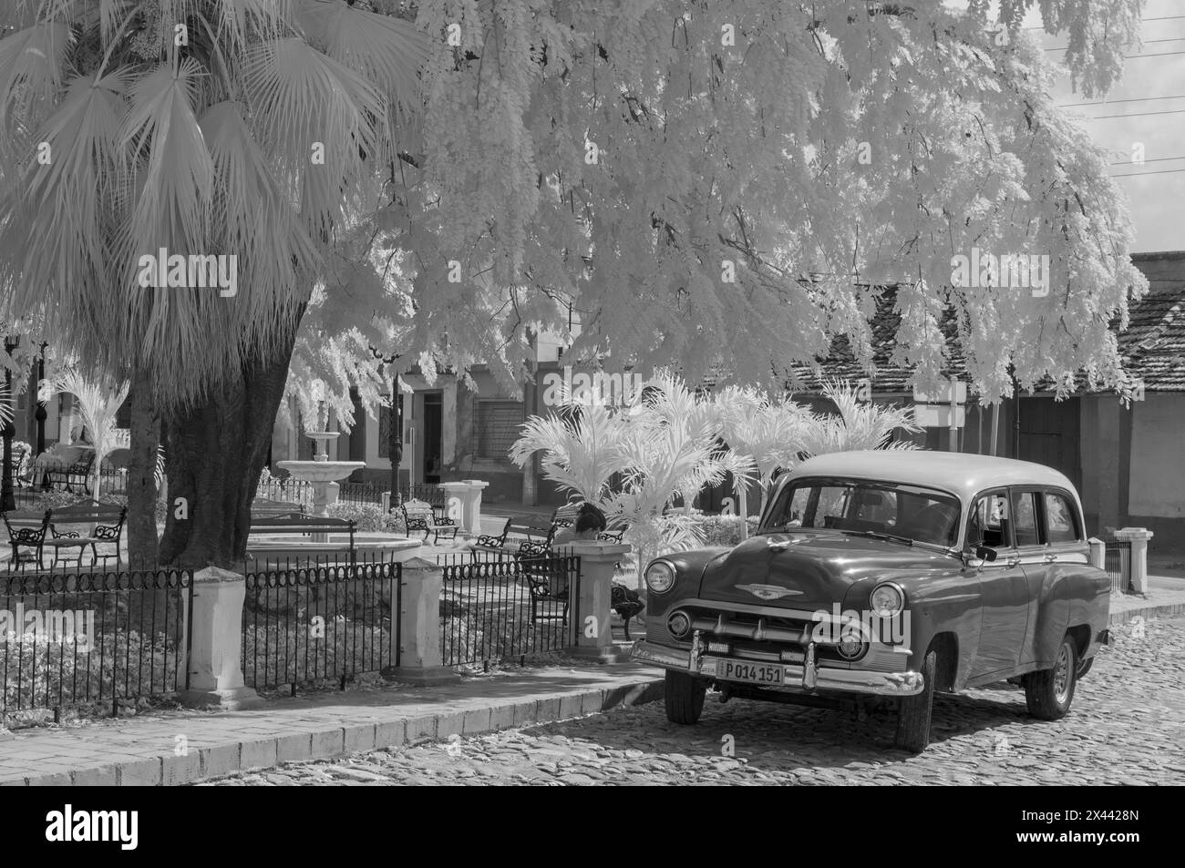 An infrared picture of a restored, vintage Classic American Car in the Plaza Sant Ana, Trinidad, Cuba. Stock Photo