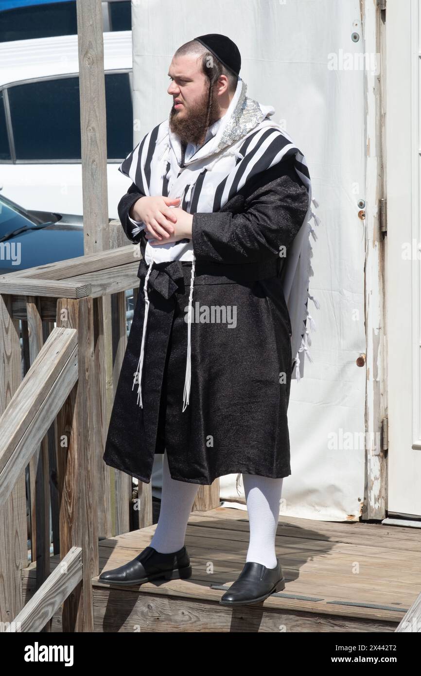 An orthodox Jewish man wearing a tallis prayer shawl and hogh white socks outside of a synagogue on Passover. In Monsey, Rockland County, New York. Stock Photo