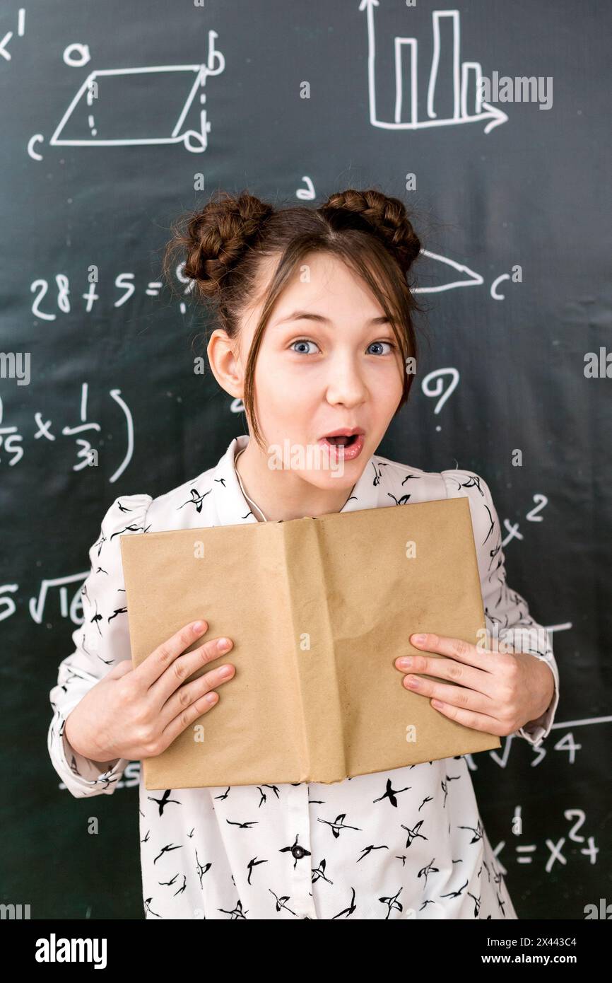 Emotional girl schoolgirl with an open book in her hands Stock Photo ...