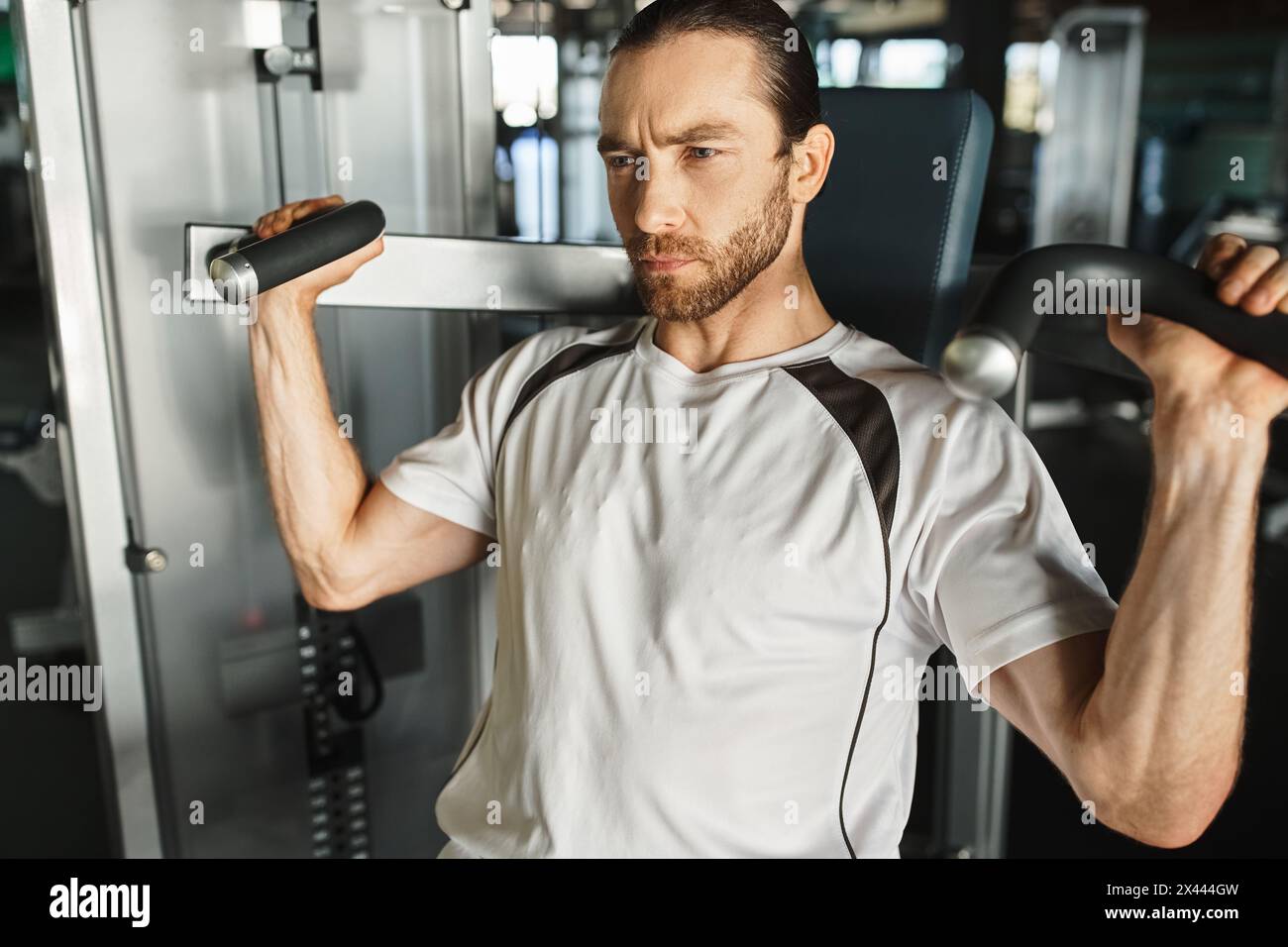 Active Working Man An athletic man in active wear, holding a handles on exercise machine ...