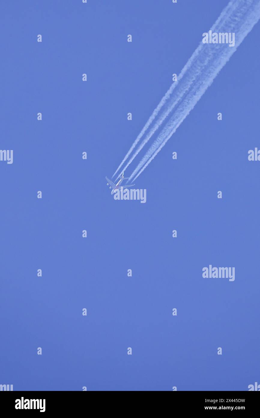 Passenger aeroplane, four-striped with condensation streaks in the blue sky, North Rhine-Westphalia, Germany Stock Photo