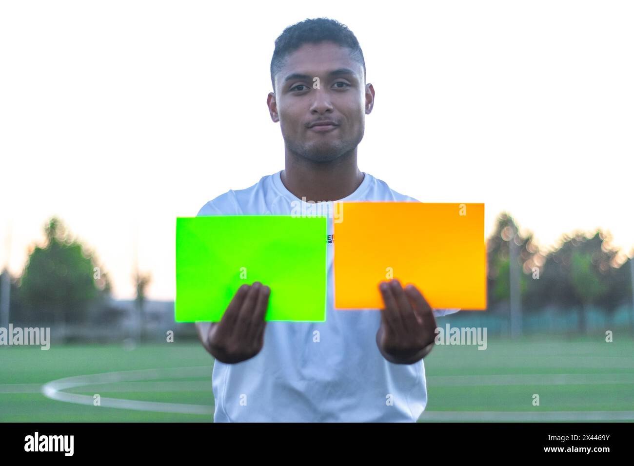 Latin Soccer referee taking out two cards on the field. Front view of soccer referee taking out cards Stock Photo