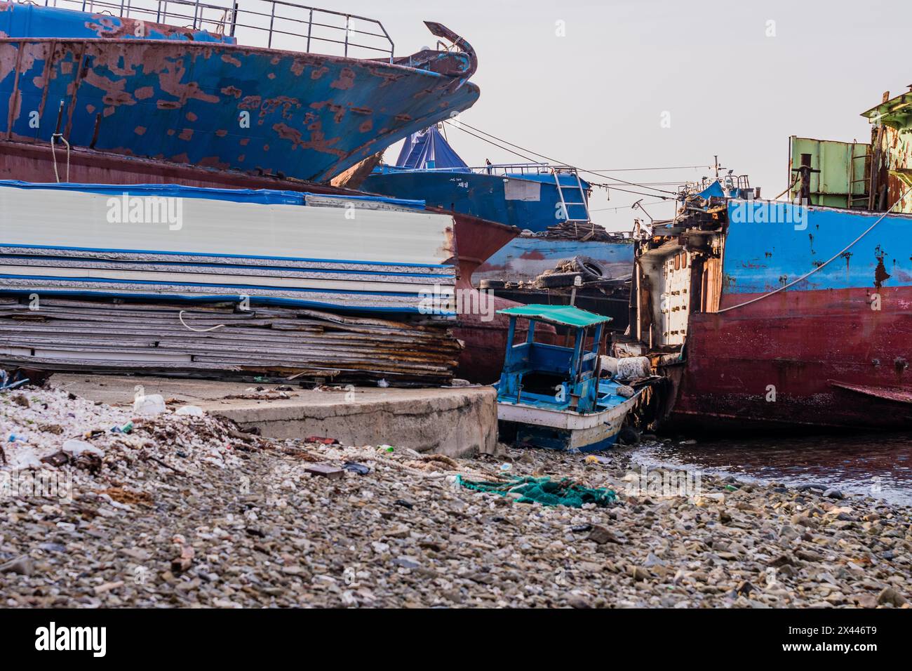Old rusty abandoned ships sitting on the shore amid trash and debris at