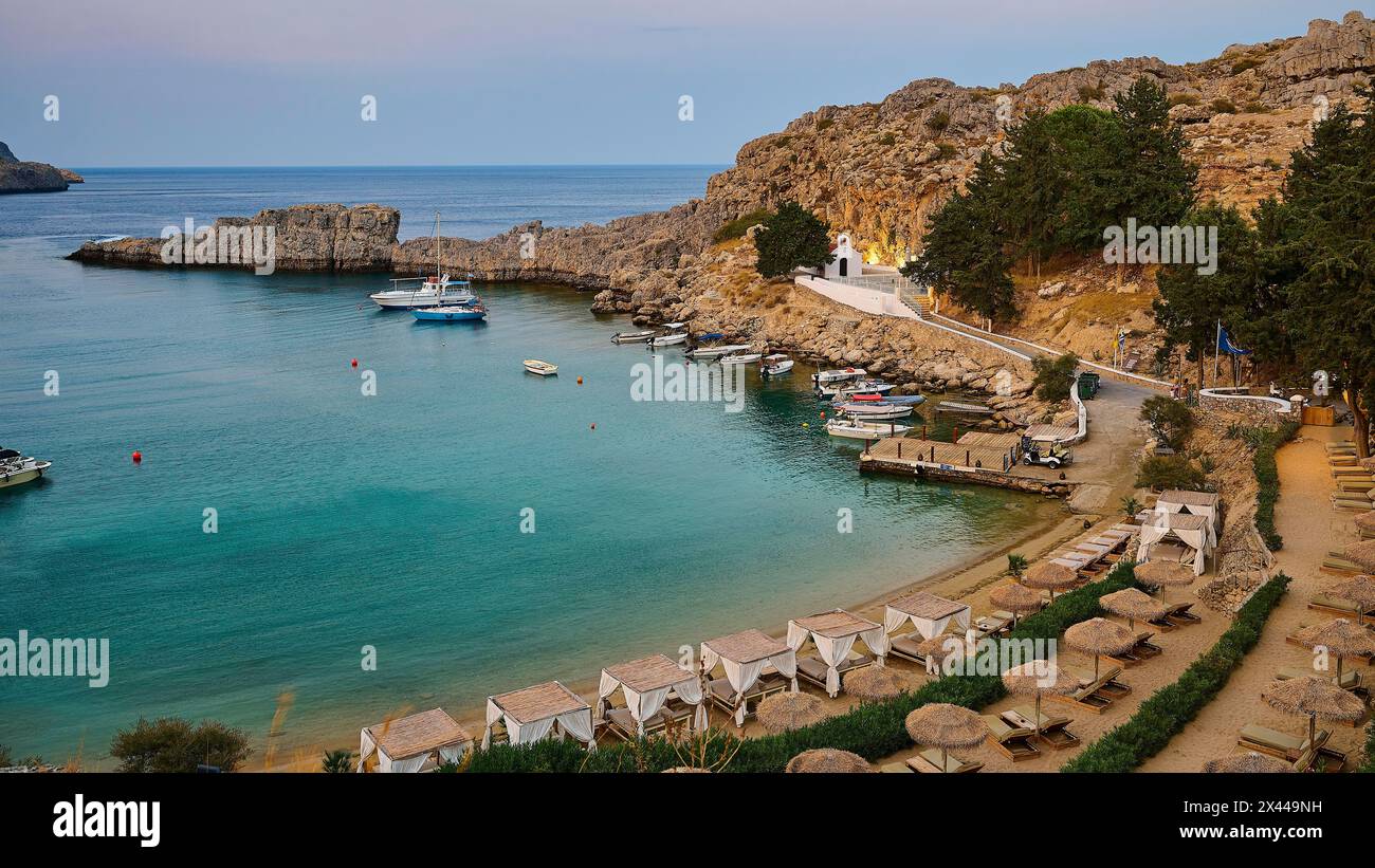 Bay with sun loungers and clear water, St Paul's Chapel, Paul's Bay, below the Acropolis of Lindos, Lindos, Rhodes, Dodecanese, Greek Islands, Greece Stock Photo