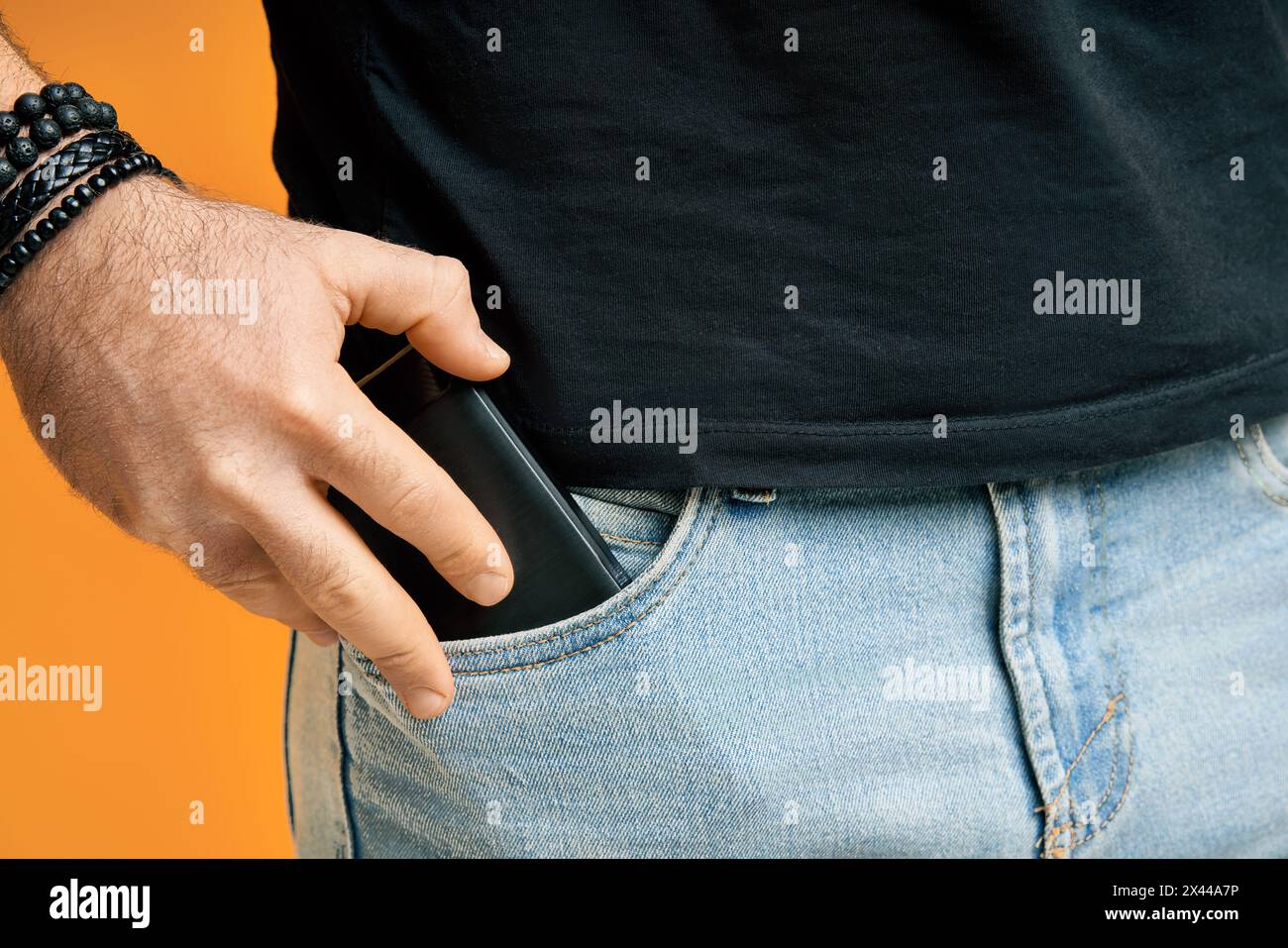 Closeup man take out mobile phone of his pocket over yellow background Stock Photo