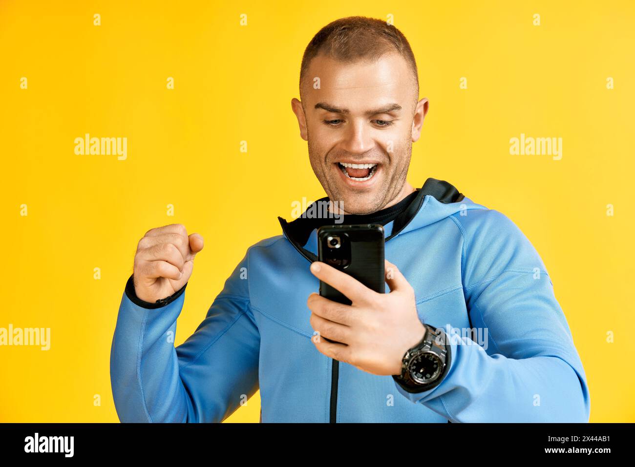 Excited screaming man holding mobile phone over yellow studio background. success concept Stock Photo