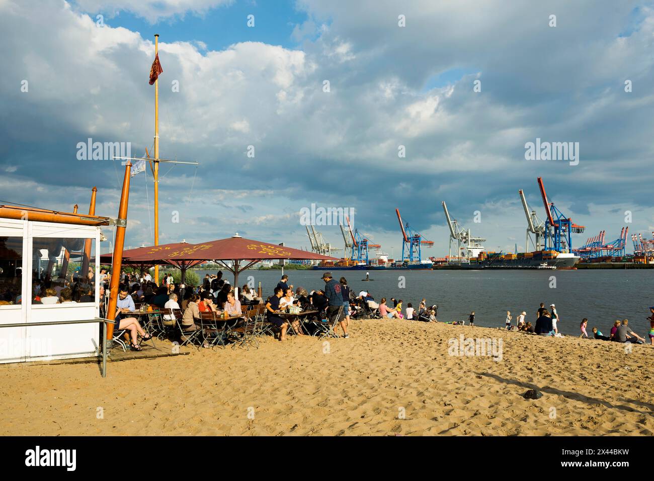 People on the beach, Strandbar Strandperle, Elbe beach, Hamburg harbour in the background, Oevelgoenne, Hamburg, Germany Stock Photo