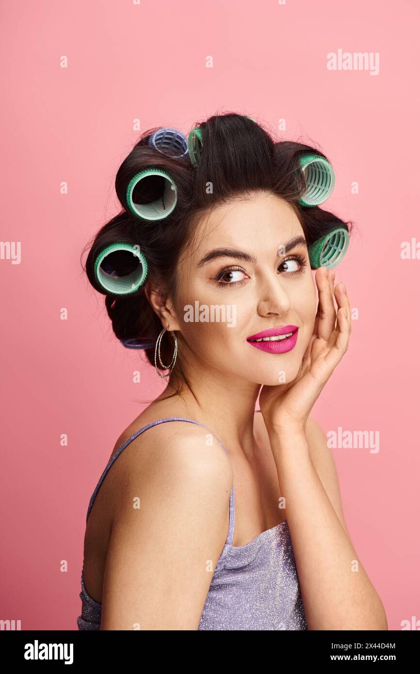 A stylish woman with curlers in her hair represents natural beauty on a vibrant backdrop. Stock Photo