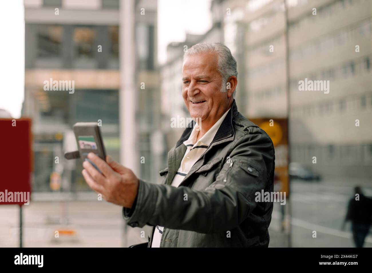 Smiling retired senior man using smart phone during video call Stock Photo