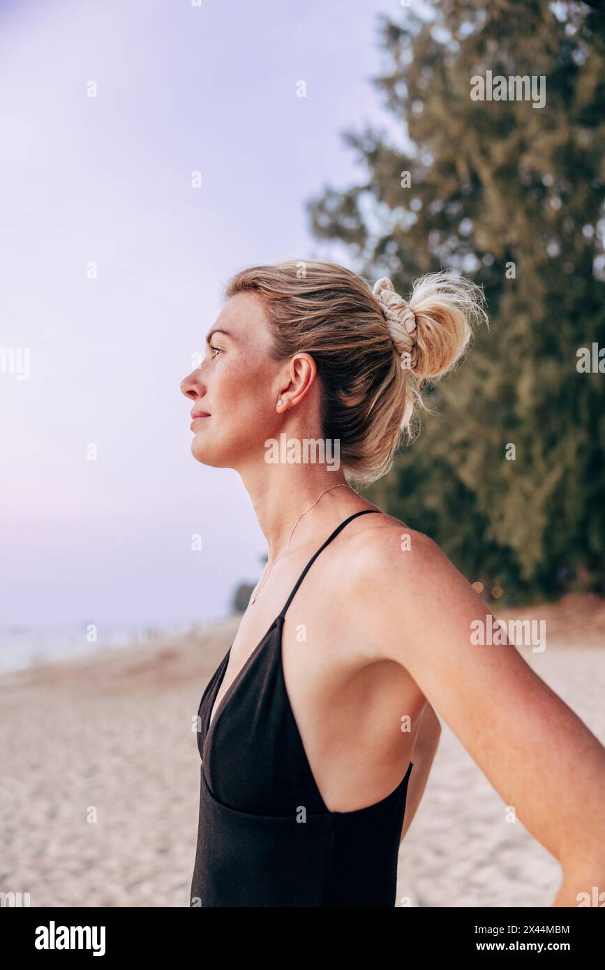 Side view of woman with hair bun looking at sea on beach Stock Photo