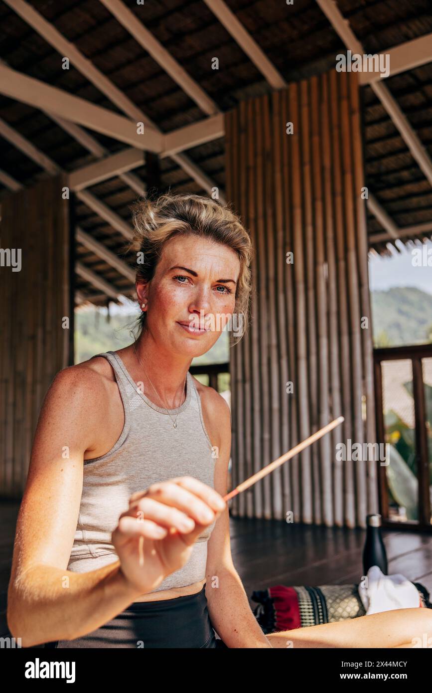Portrait of woman holding incense stick at wellness resort Stock Photo
