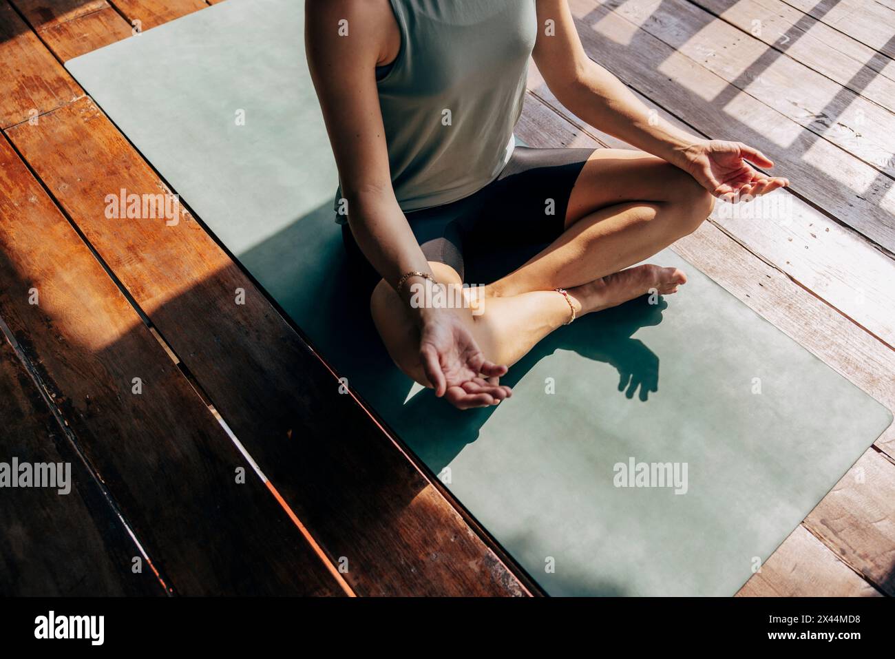 Low section of woman practicing yoga while sitting on exercise mat at wellness resort Stock Photo