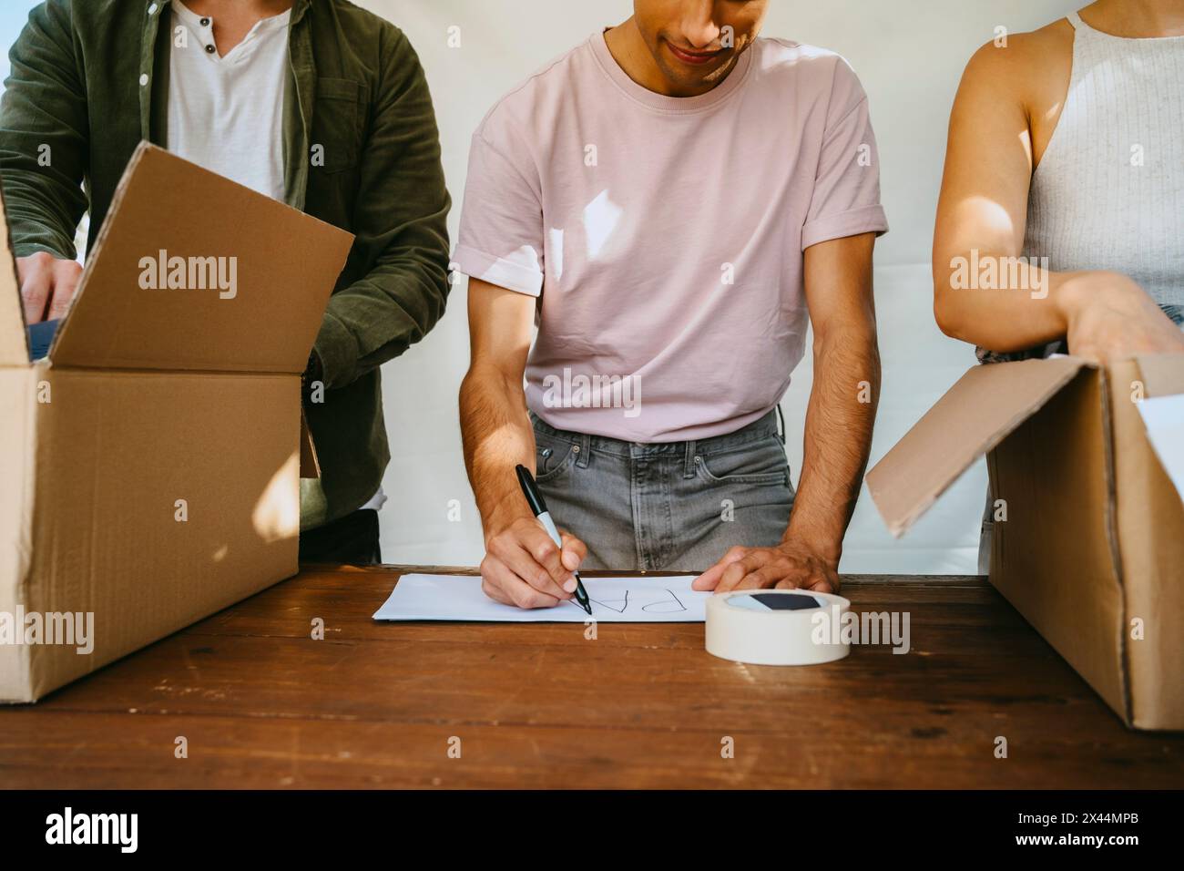 Male volunteer making name tag while standing with colleagues near table at community center Stock Photo