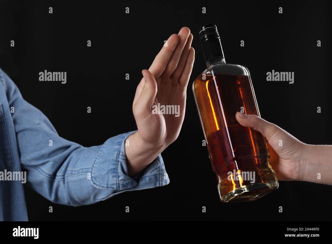 Alcohol addiction. Man refusing bottle of whiskey on black background ...