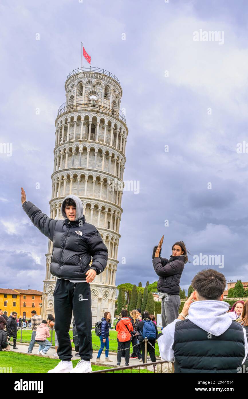 Tourists trying to look like they are propping up the Leaning Tower of Pisa (Torre di Pisa). The tower is the most popular attraction in Pisa. Stock Photo