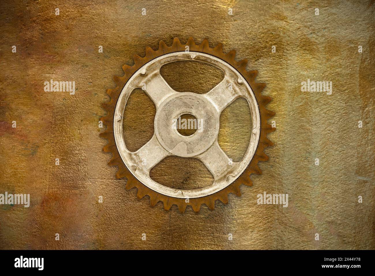 Old weathered gear wheel on a brass background Stock Photo