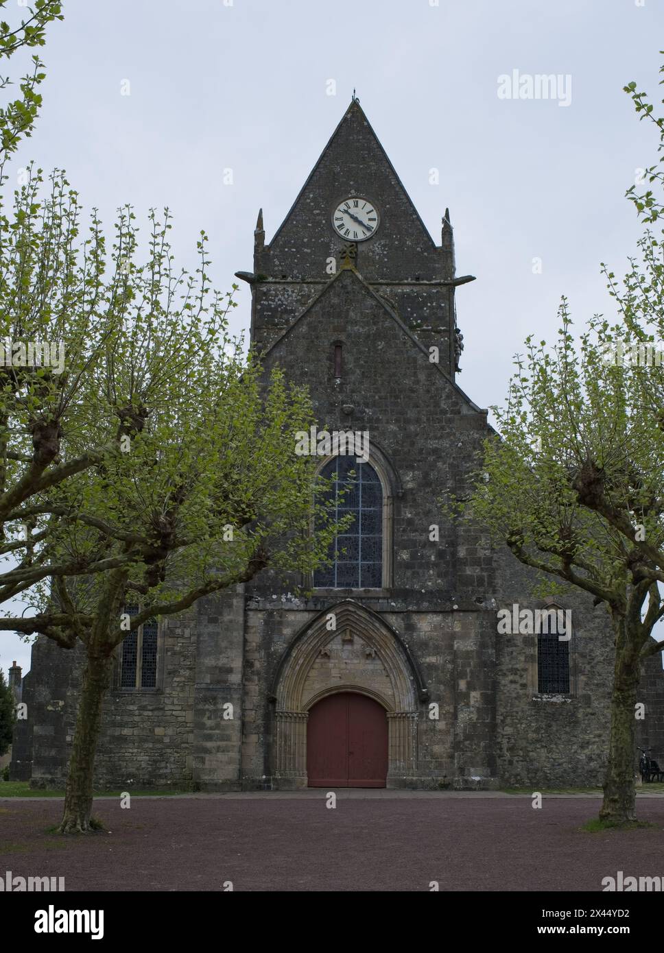 Sainte-Mere-Eglise, France - Apr 19, 2024: Sainte-Mere-Eglise church. People walking in Sainte-Mere-Eglise. Streets and buildings. Lifestyle in the ur Stock Photo