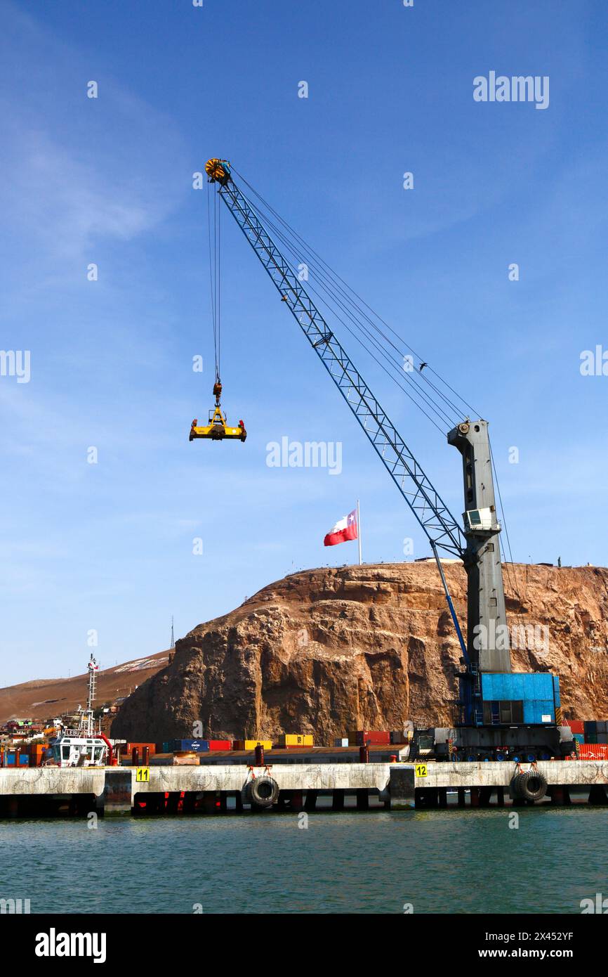 Mobile crane with a spreader for lifting containers in port, El Morro headland in background, Arica, Chile Stock Photo
