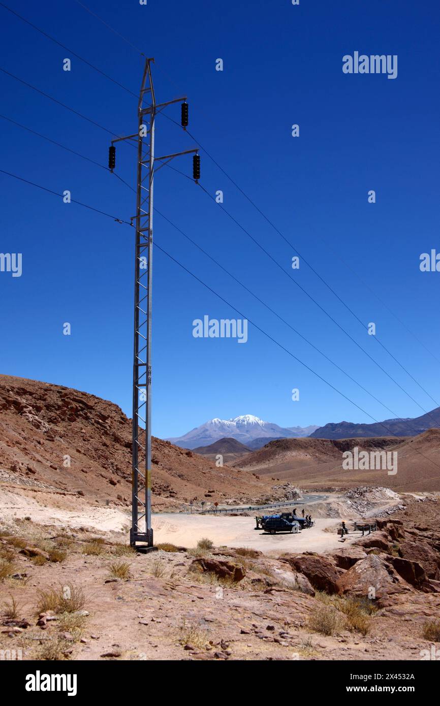 Electricity pylon and car park next to Highway 11 at Copaquilla, Nevados de Putre / Taapaca volcano in background, Arica and Parinacota Region, Chile Stock Photo