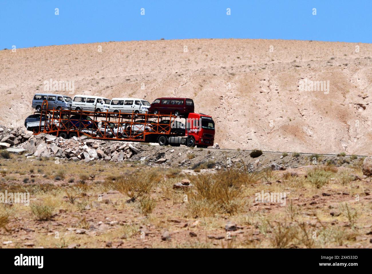 Truck and car-carrying trailer heading towards Bolivia through Atacama Desert on Ruta /  Highway 11, Chile Stock Photo