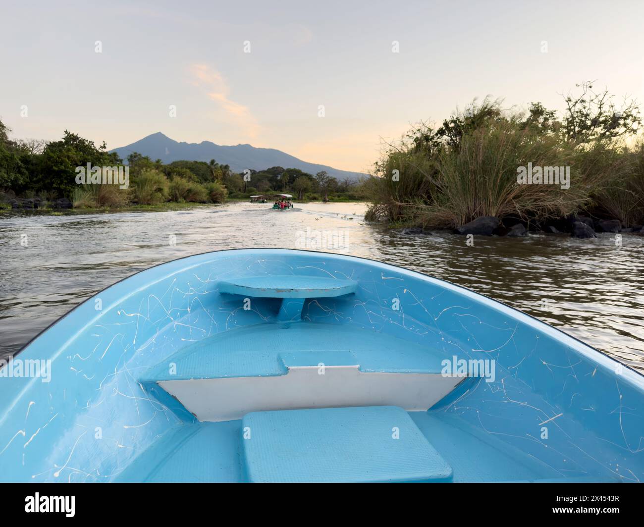 Blue boat on tour in lake with sunset volcano background Stock Photo