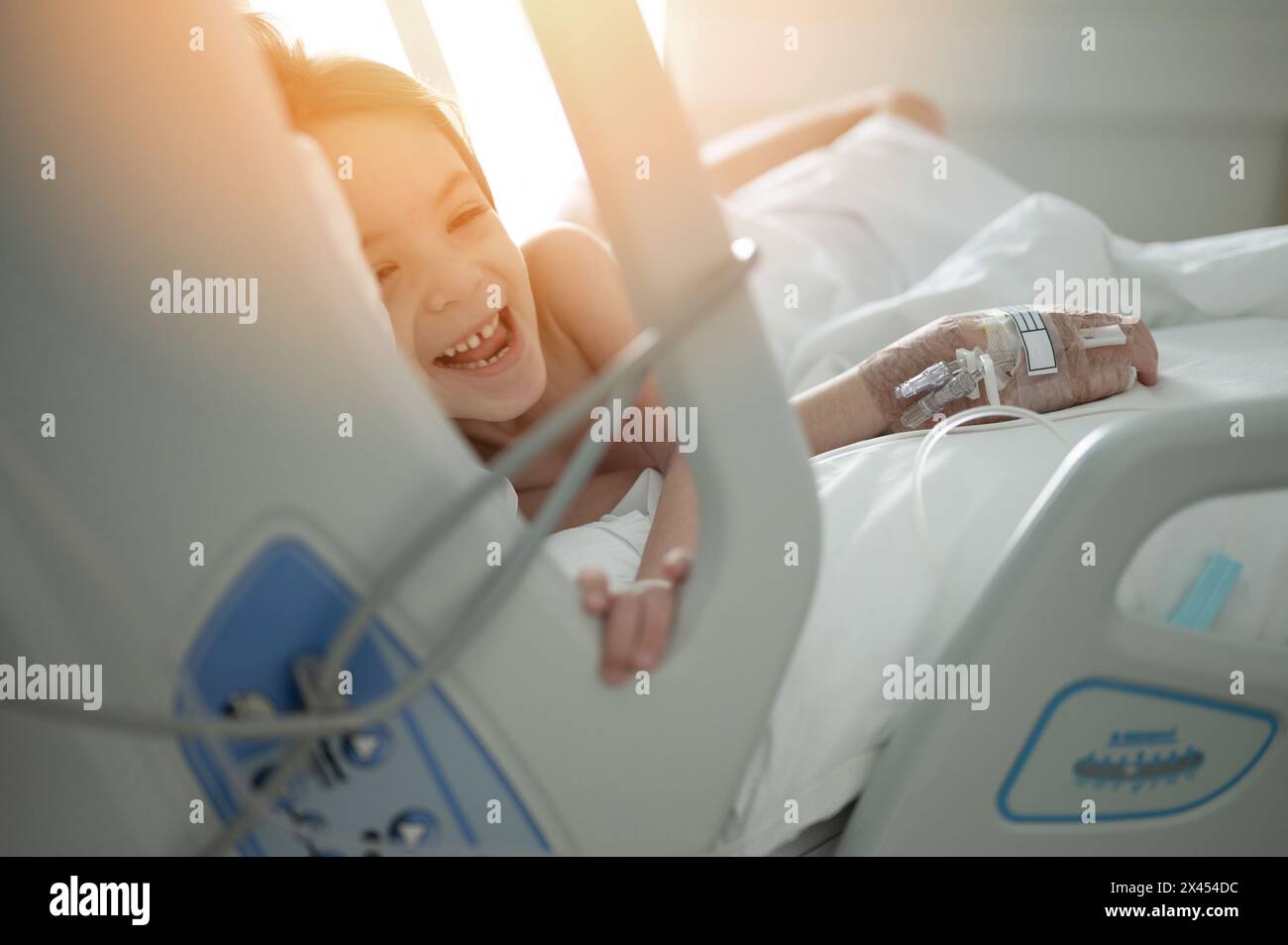 Smiling kid girl in hospital bed with treatment iv from illness Stock Photo
