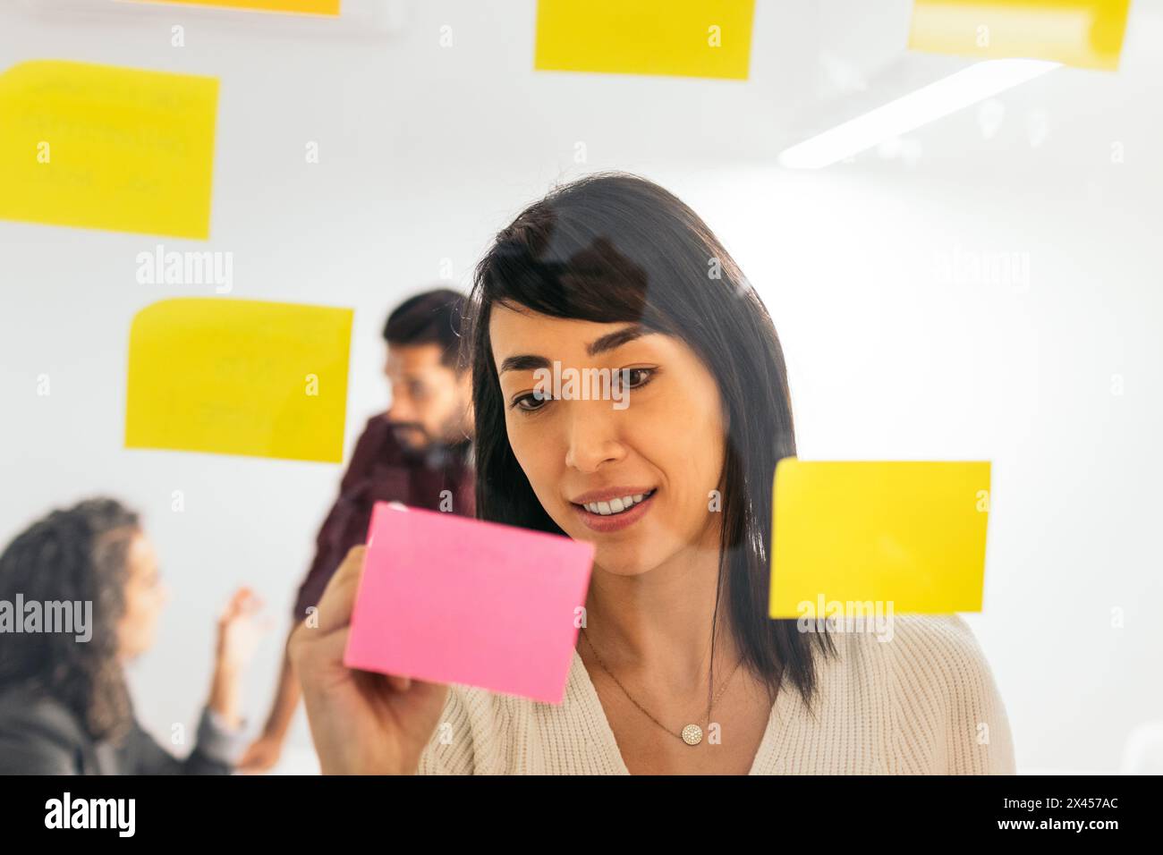 Asian woman writing on sticky notes brainstorming ideas from company meeting in coworking space Stock Photo