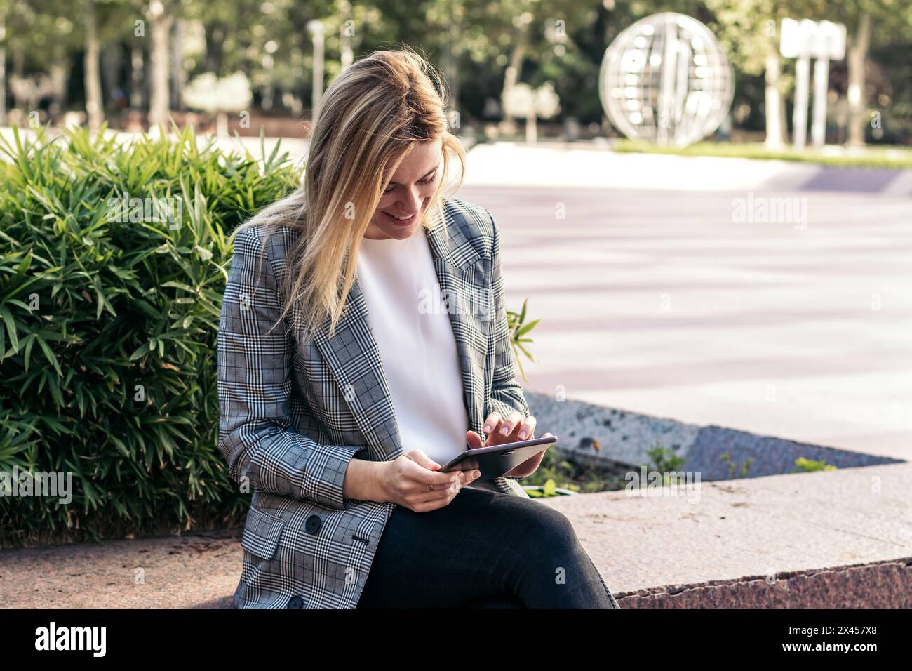 blonde business woman in a suit using a tablet outside and smiling Stock Photo