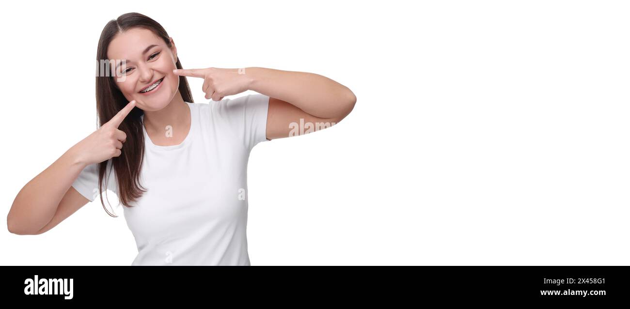 Smiling woman pointing at her braces on white background. Banner design with space for text Stock Photo