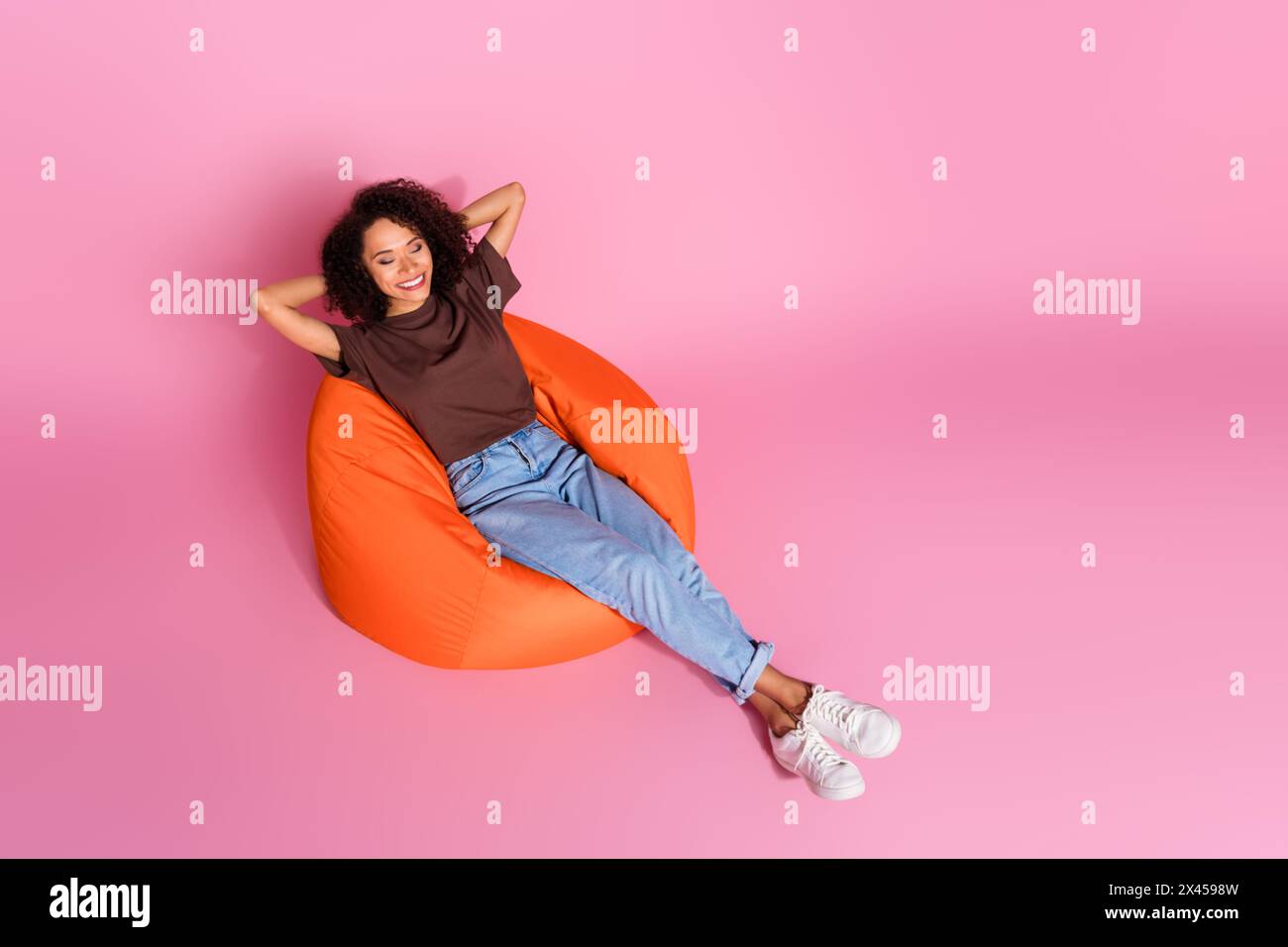Full body photo of attractive young woman sleeping sit bean bag dressed stylish brown clothes isolated on pink color background Stock Photo
