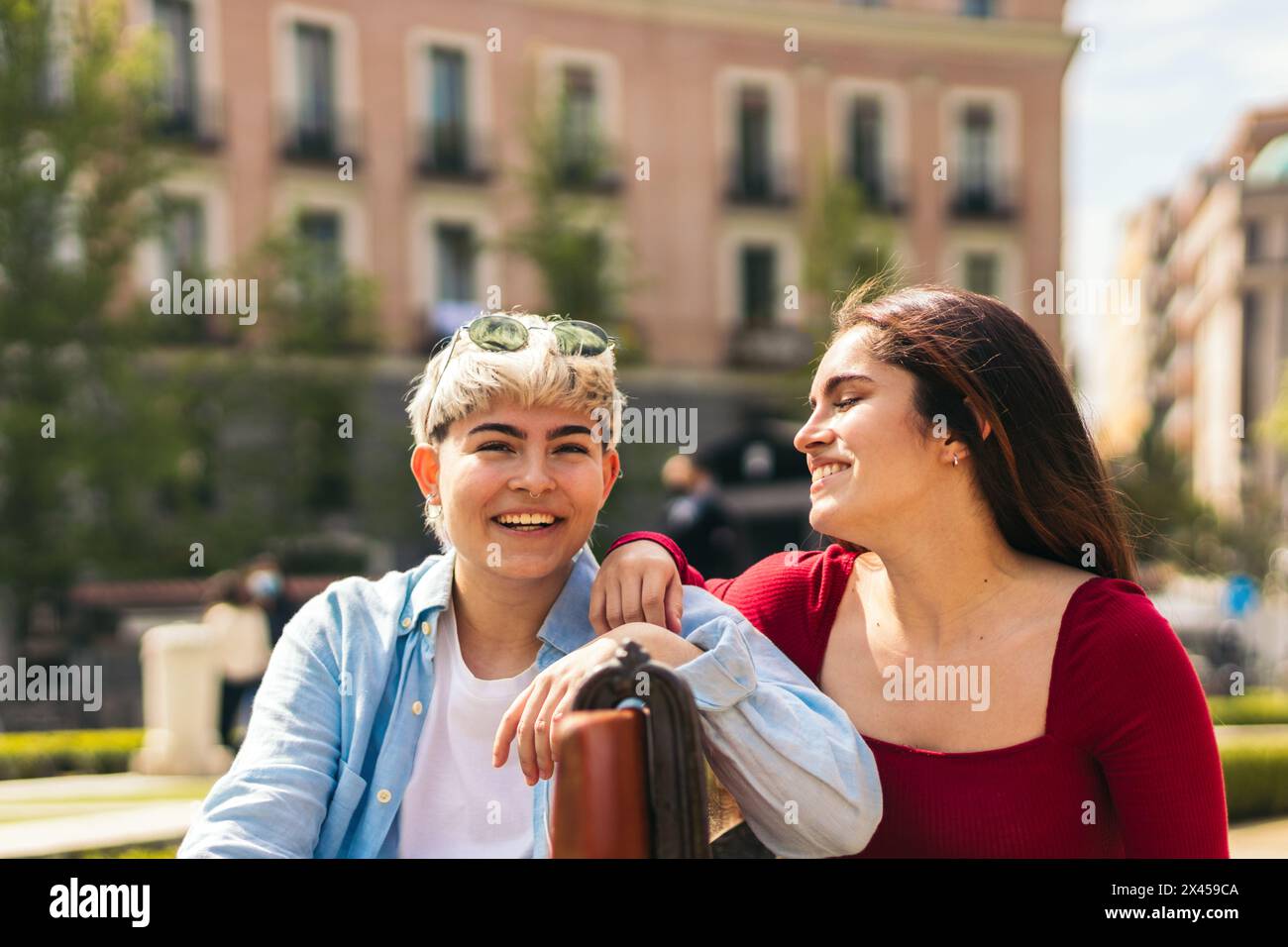 two teenager girls laughing and smiling sitting on a bench Stock Photo ...