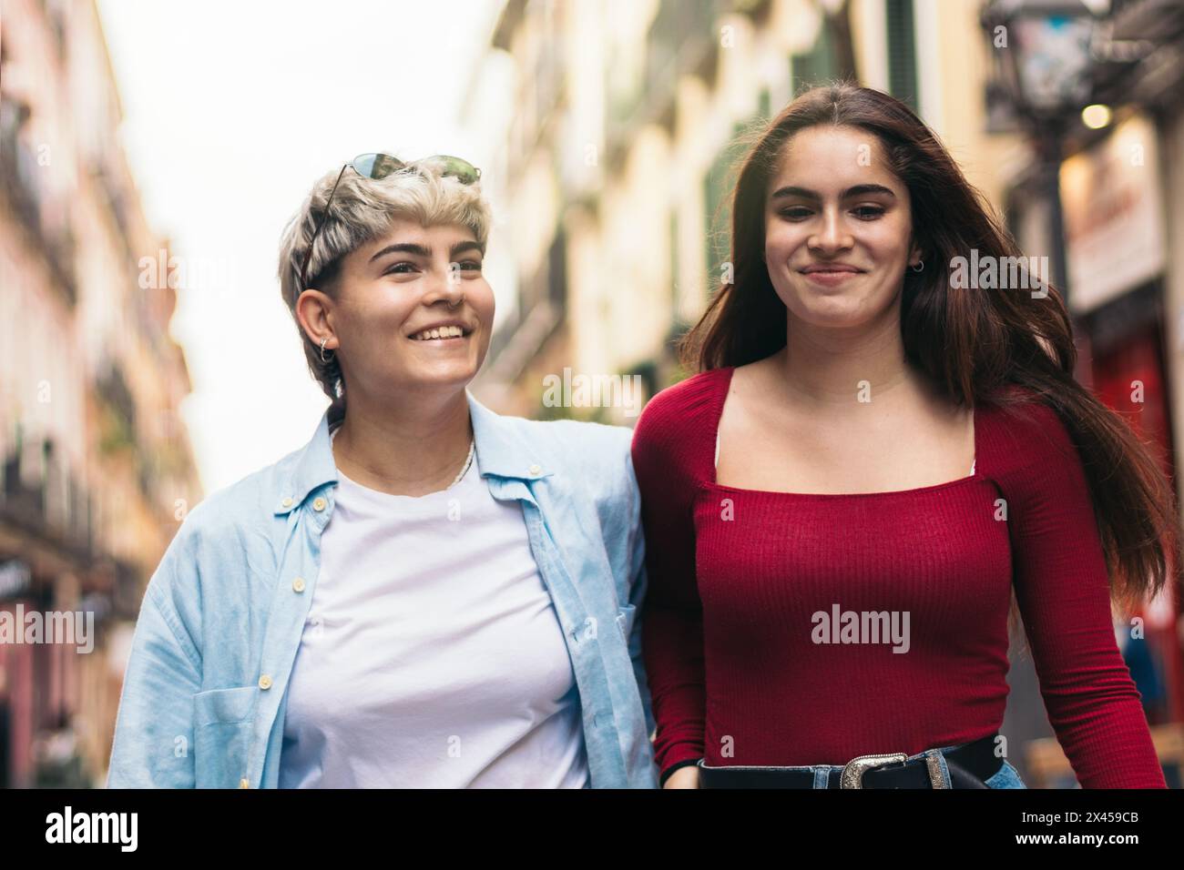 two teenager girls walking and smiling on a street Stock Photo - Alamy