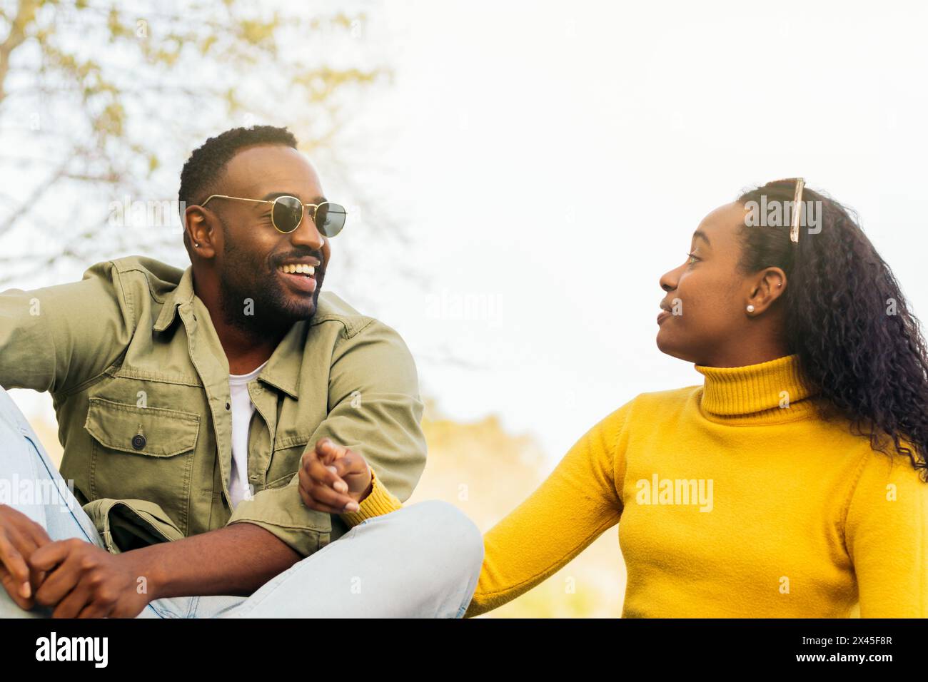 attractive black couple talking sitting in a park Stock Photo
