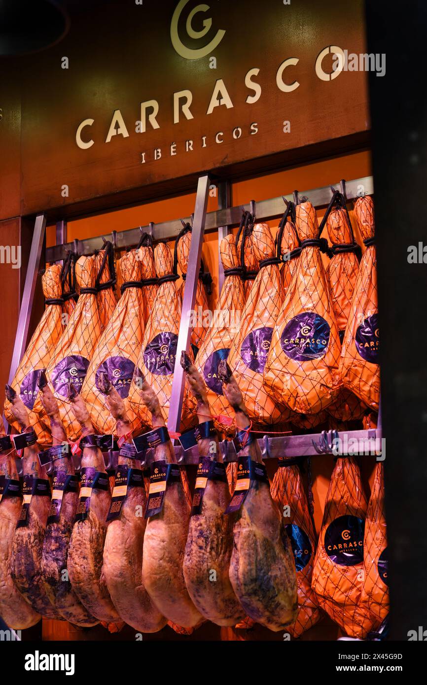 Madrid, Spain. February 11, 2024 - Legs of Dry-cured Iberian Ham (Jamon) hanging on a wall in Mercado de san miguel. Stock Photo