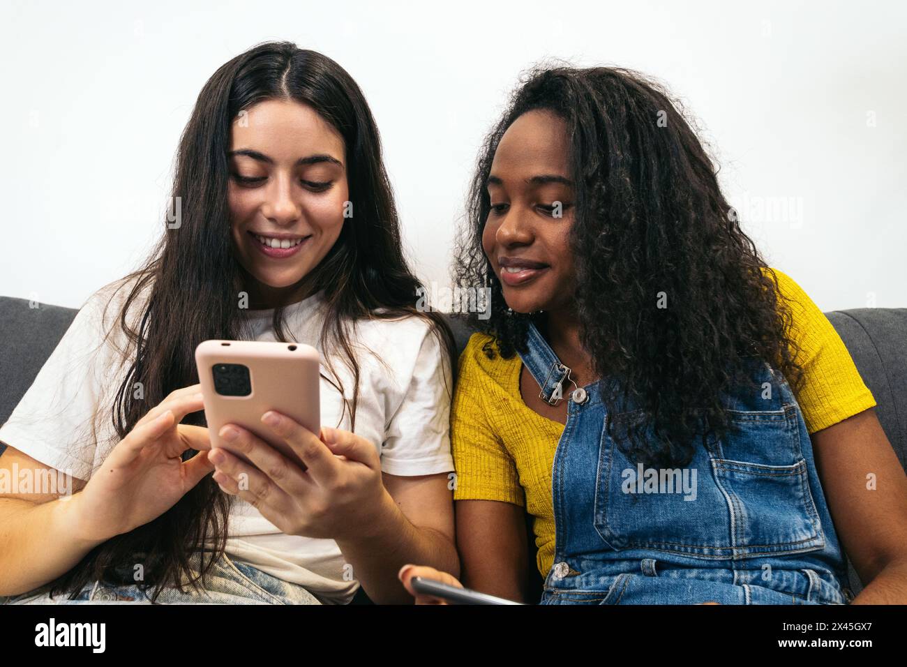Connected at home: Two young women using mobile devices Stock Photo