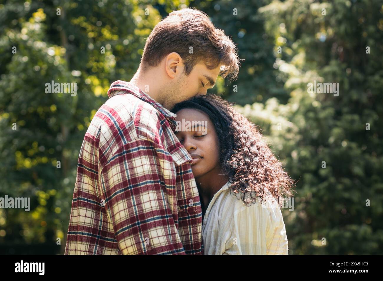 Interracial young couple hugging and kissing in the park Stock Photo ...