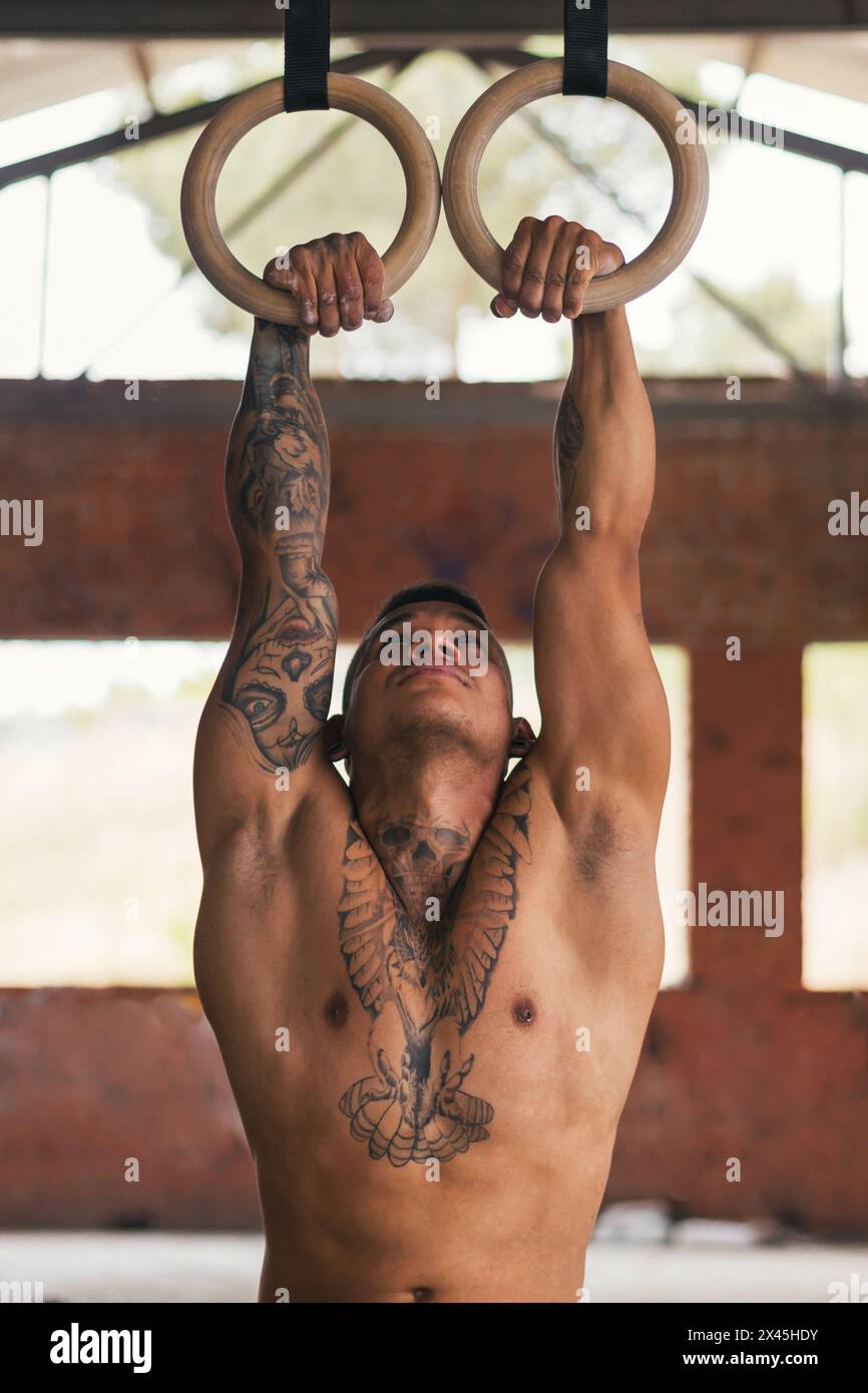 man athlete doing pull ups in gymnastic rings Stock Photo