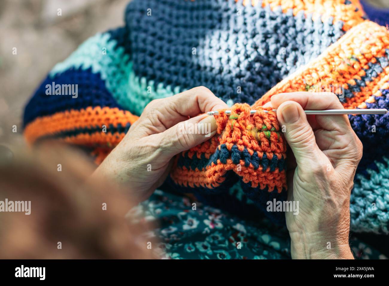 Elderly woman crocheting a blanket. She is concentrating on her task ...
