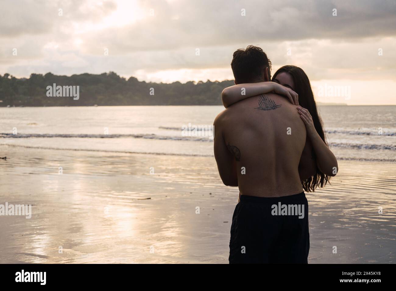 Romantic photo of a couple embracing on the beach watching sunset Stock ...