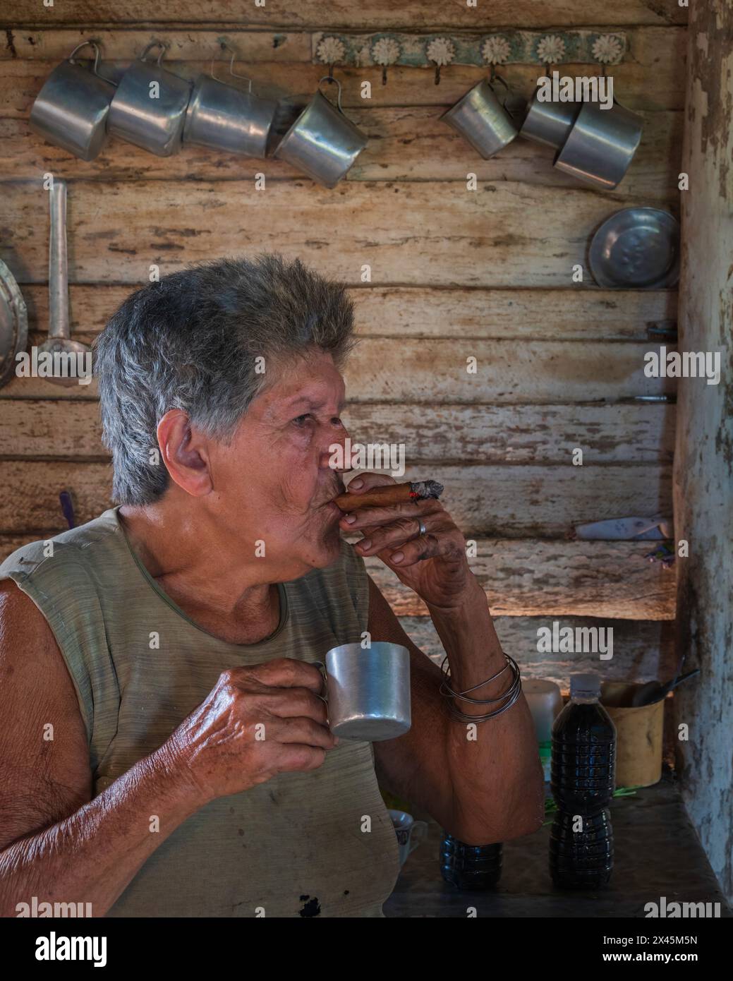 A coffee farmers wife smoking a cigar in the farmhouse while making the coffee, near Vinales, Cuba Stock Photo