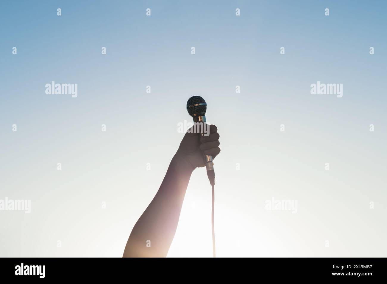 man hand holding a microphone outdoors with sunlight reflects Stock Photo