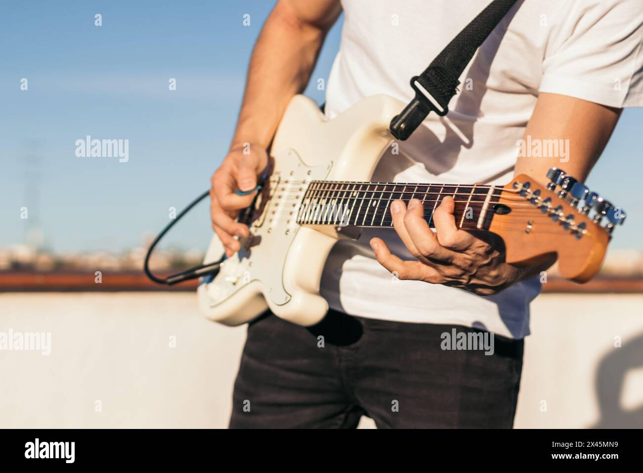 man playing electric guitar on a rooftop. close-up Stock Photo