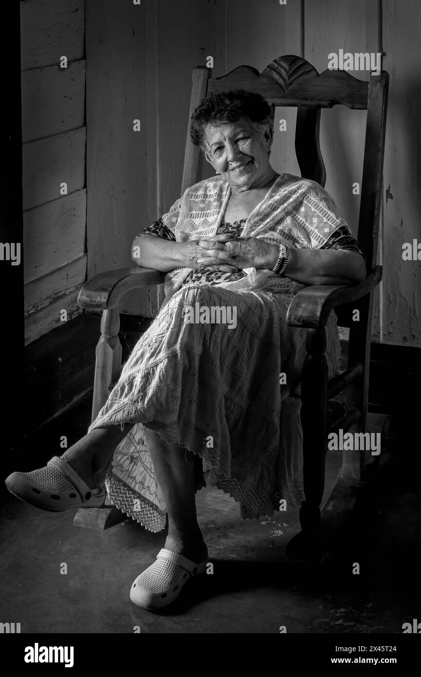An elderly lady sat in a rocking chair in the fam house of Benito’s Tobacco farm, Vinales National Park, Vinales, Cuba Stock Photo
