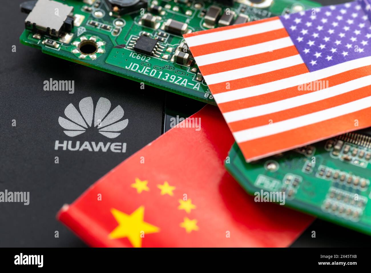London. UK- 04.26.2024. A technology political economic concept. The logo of the Chinese tech company Huawei, a circuit board and the Chinese and Amer Stock Photo