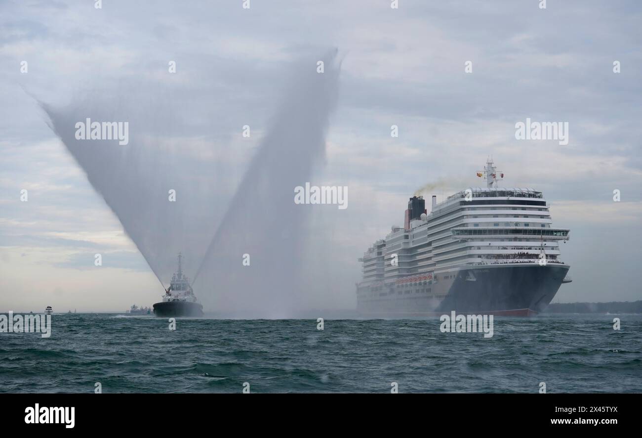 A tug boat sprays water as Cunard's newest cruise ship Queen Anne arrives at the City Cruise Terminal in Southampton, Hampshire, after sailing from the Fincantieri Marghera shipyard in Venice following five years of construction in Italy. The cruise liner can hold three thousand guests and will undertake her maiden voyage next month. Picture date: Tuesday April 30, 2024. Stock Photo