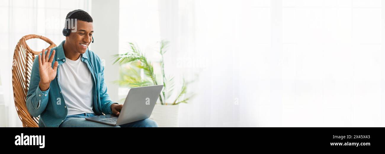 Man in headphones using laptop and waving Stock Photo