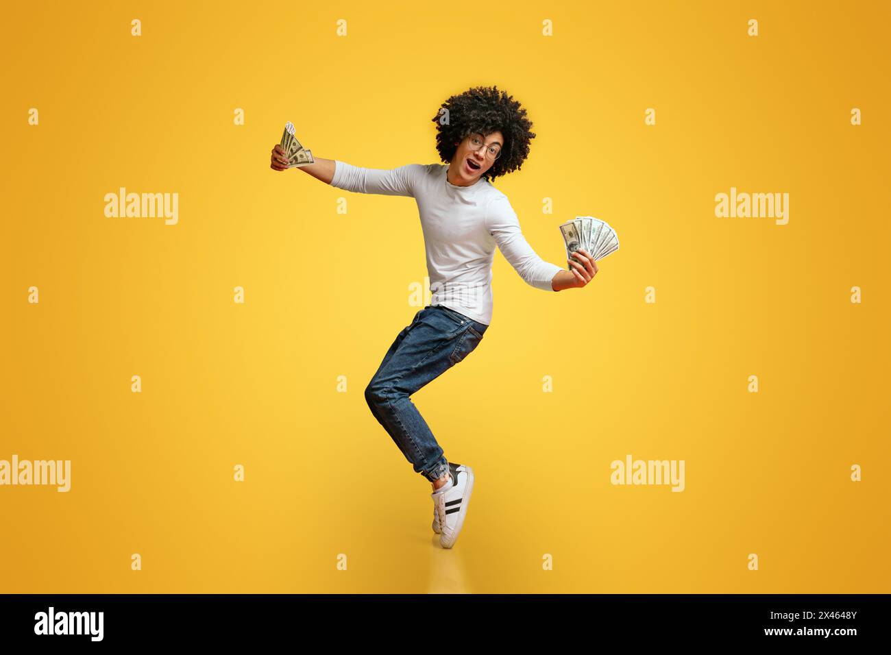 Happy african american guy dancing on tiptoes with money fans Stock Photo