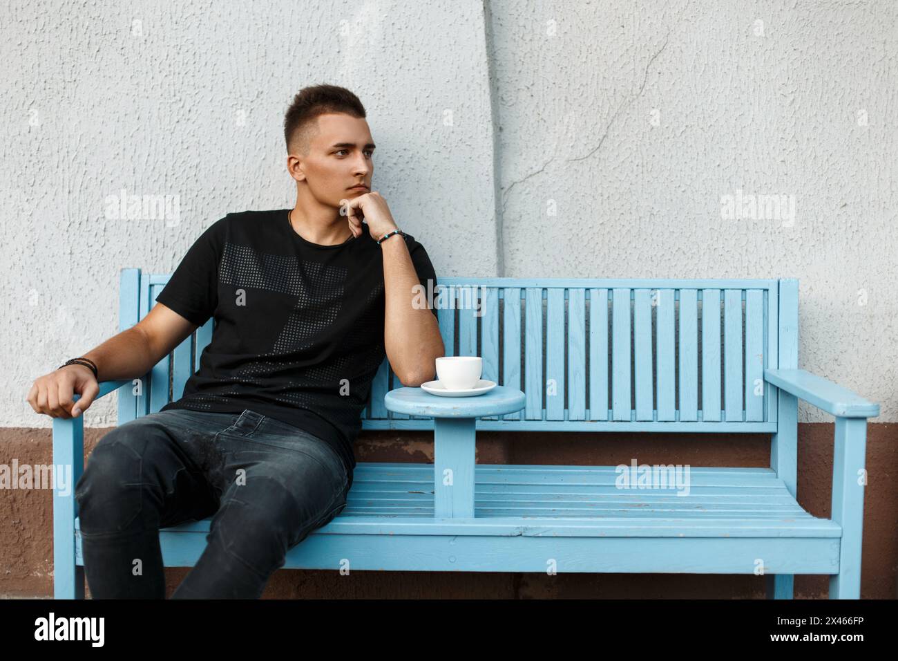 Handsome Lonely Man Sits Alone On A Bench And Drink Coffee Stock Photo