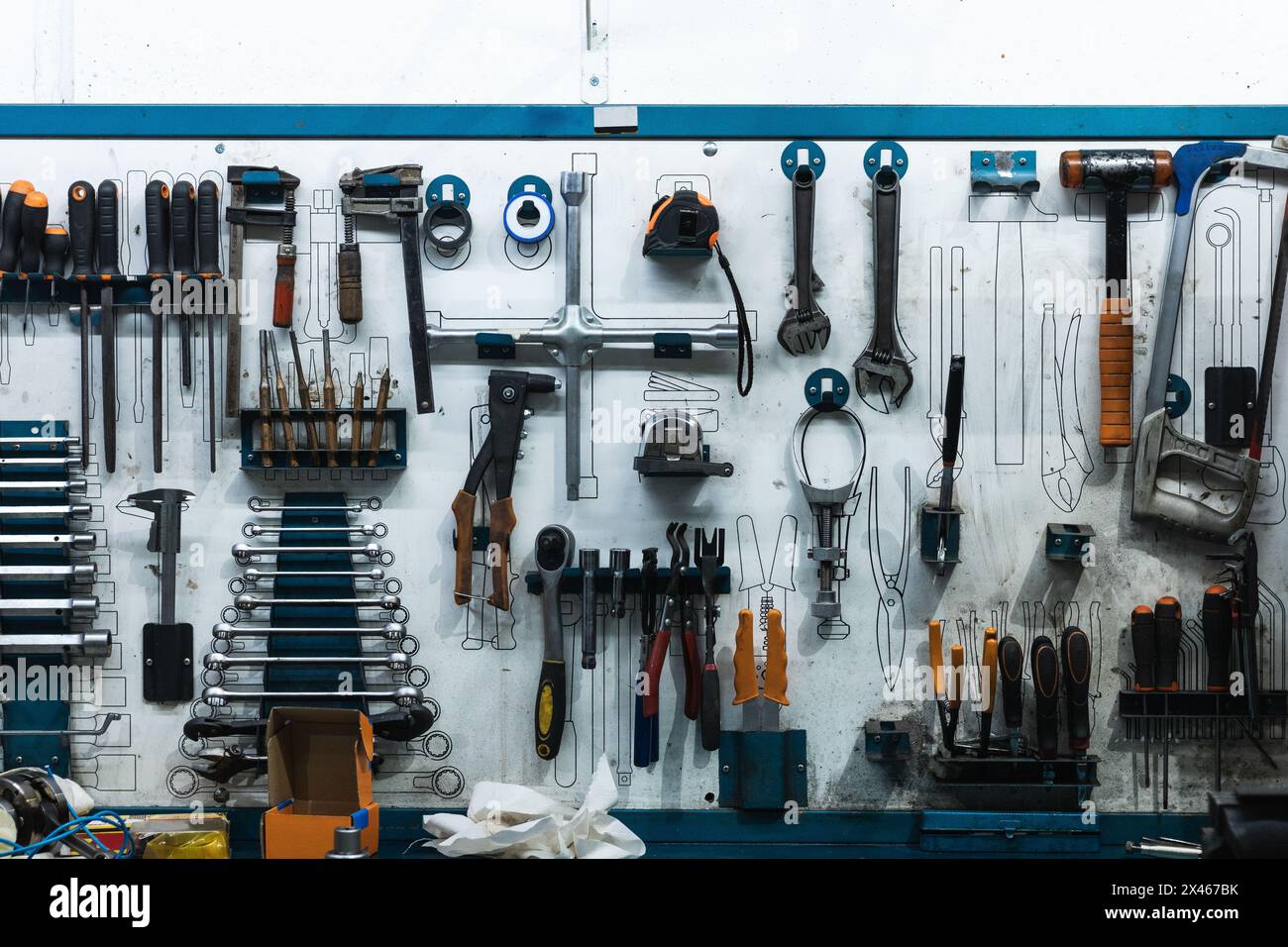Set of screwdrivers and wrenches hanging on wall with assorted auto mechanic tools in garage Stock Photo